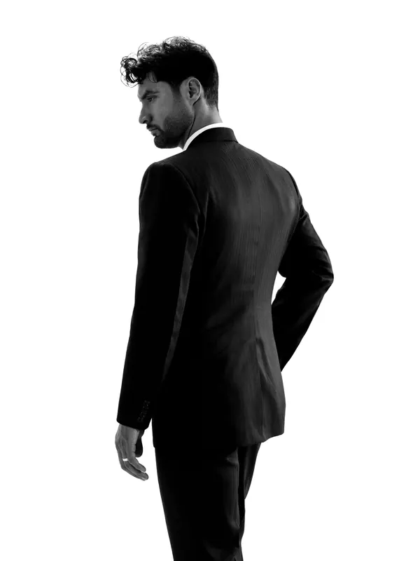 Homme mince en costume noir ajusté vu de dos, en silhouette sur fond blanc